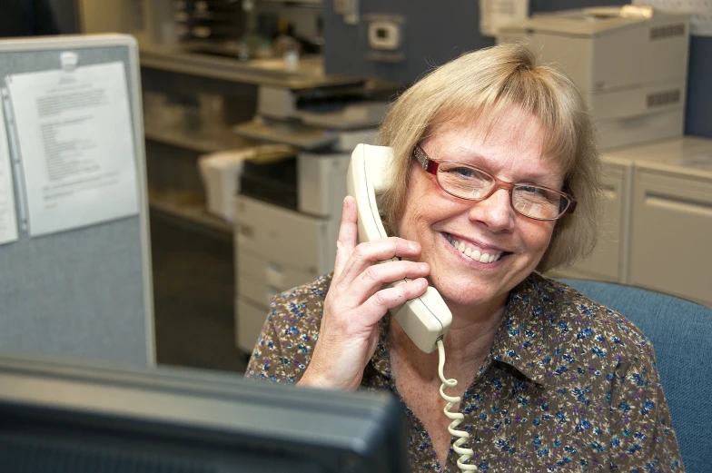 a woman in an office is talking on a telephone