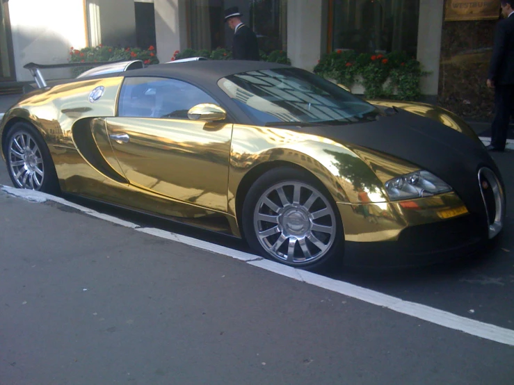 a gold colored bugatti parked on the side of a street