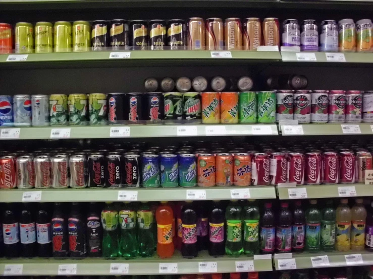 soda, water and beer bottles stacked on shelves in a cooler