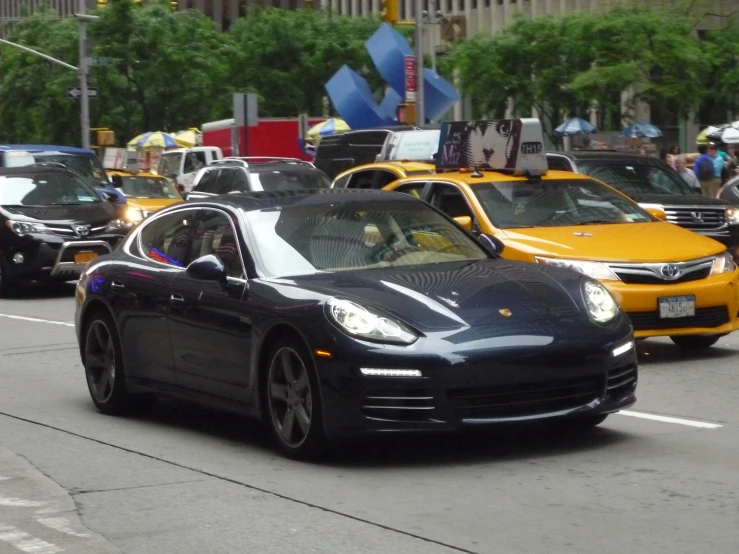 a car is driving down the street in front of some taxis