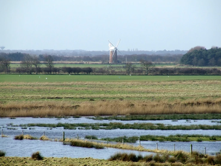 a po of a water and a windmill in the distance