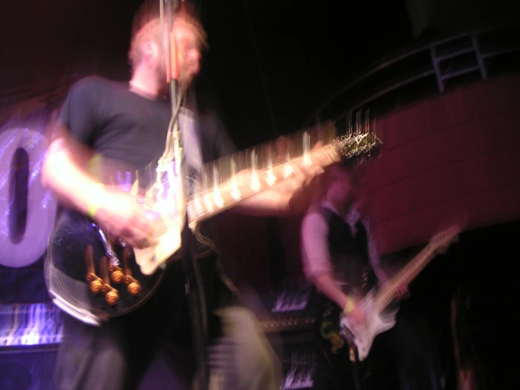 a man plays a guitar while another plays an acoustic instrument