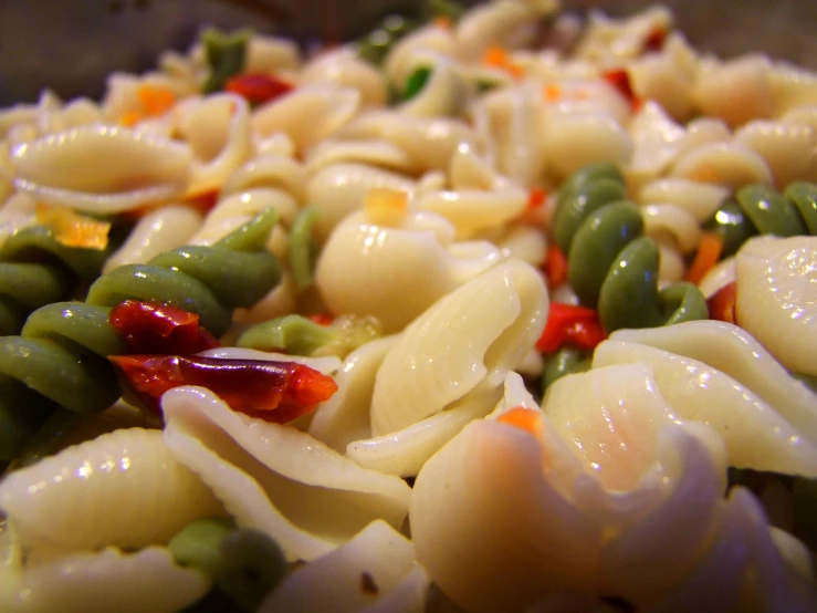 a close up of pasta with vegetables mixed in it