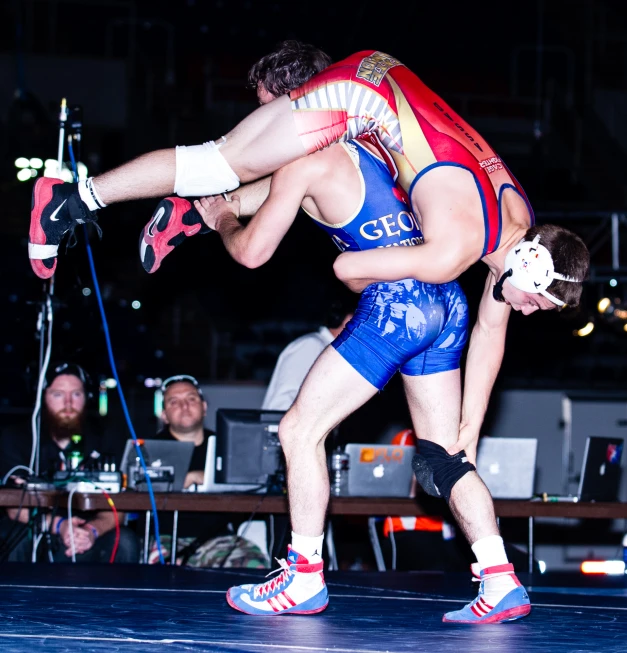 two wrestlers fighting in a wrestling ring with one holding another