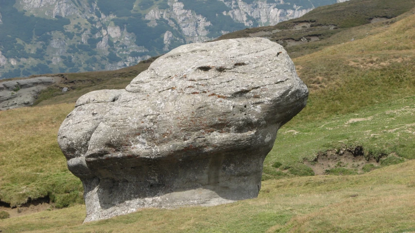 a big rock sticking out of the ground with a valley behind it