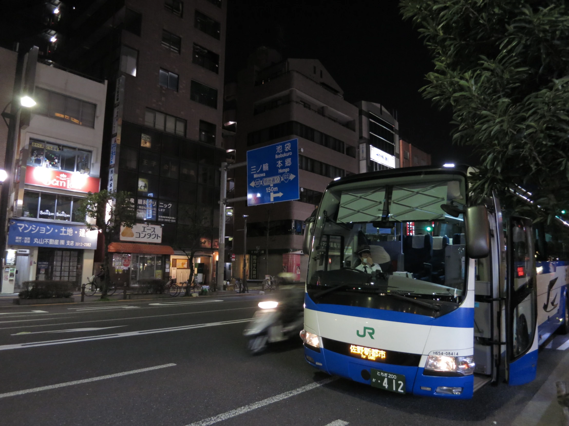 a blue and white bus sitting at a stop in the middle of a city