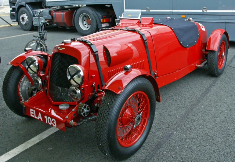 an old classic racing car is parked in a parking lot