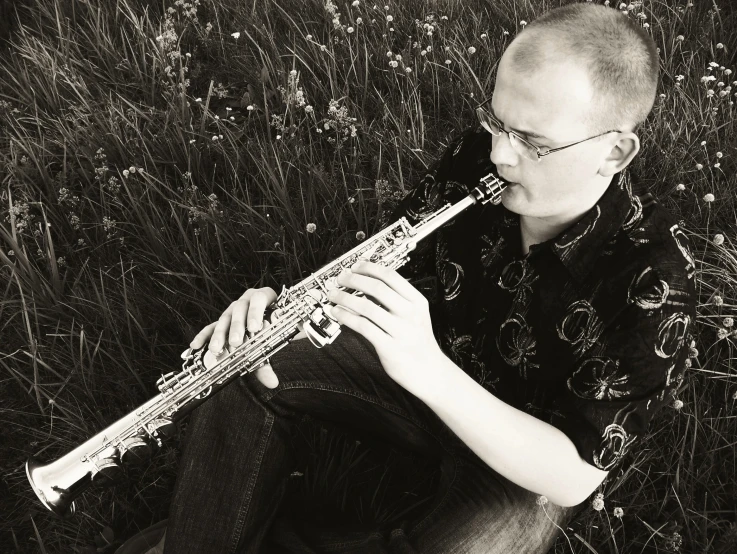 a man with glasses playing the recorder in a field