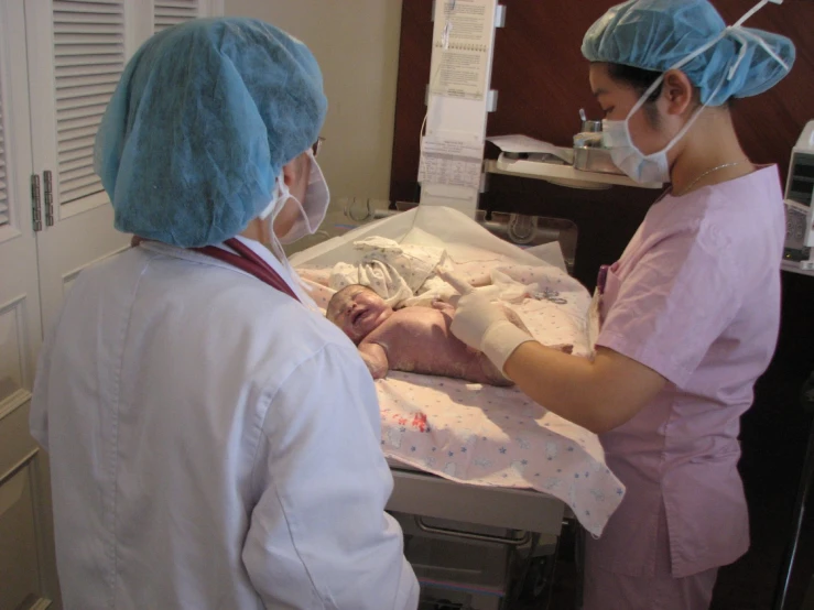 a woman doctor with protective mask and sterile clothing holds a newborn