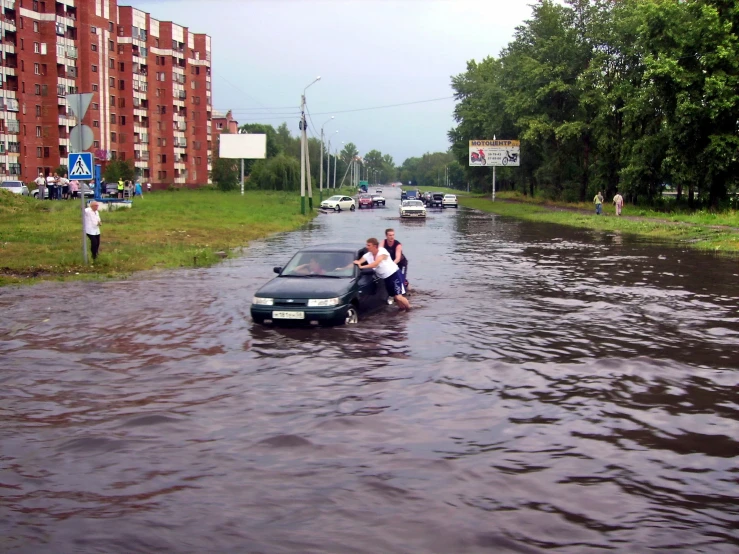 a group of people standing by a flooded car