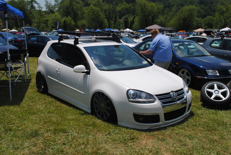 two men looking at some cars parked near one another