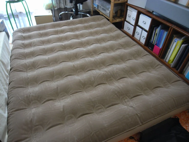 an inflatable mattress rests on the floor by bookshelves