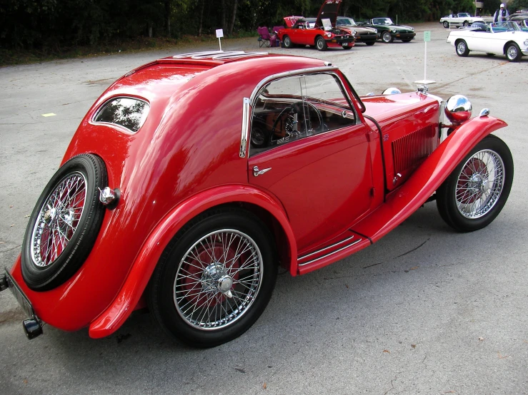 an old style red car is parked in the street