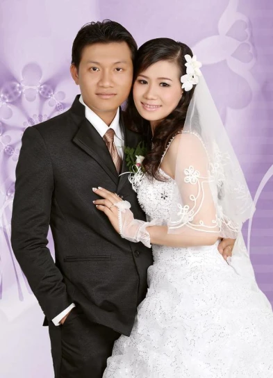 an asian couple on their wedding day standing in front of a wall