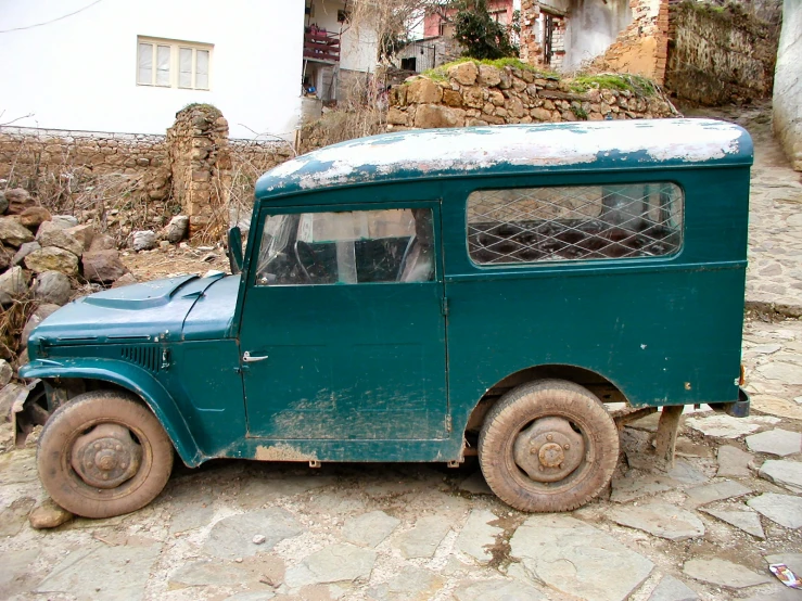 a vintage car sits on cobblestone road