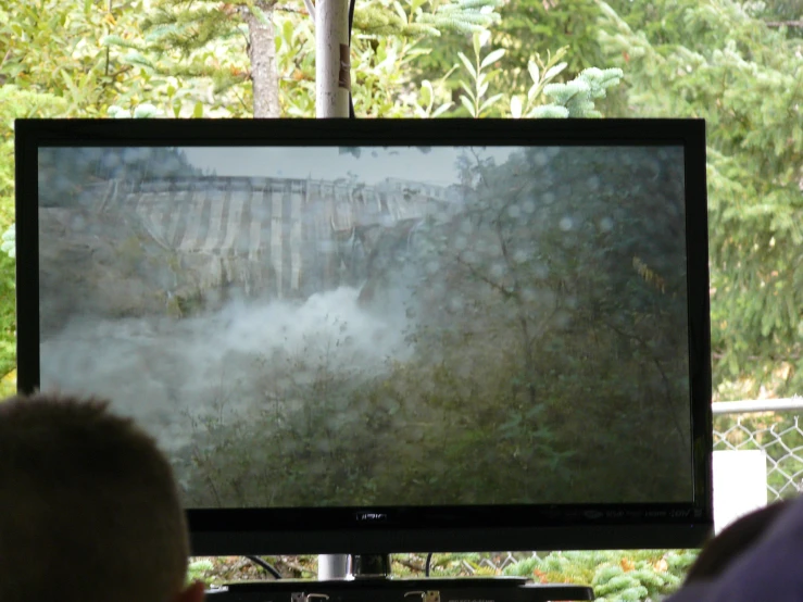 a man standing in front of a television in a forest