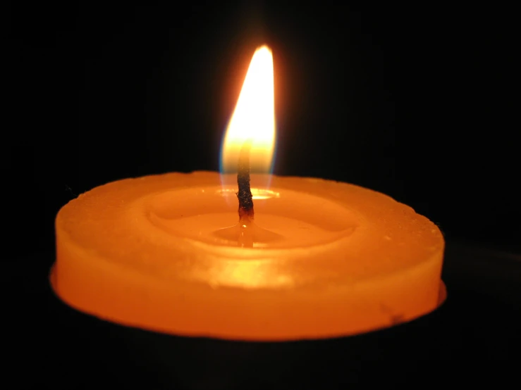 an orange candle with a dark background and one single candle lit