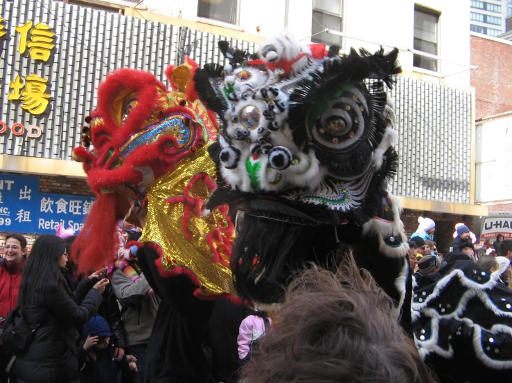 a chinese lion costume being carried through a crowd