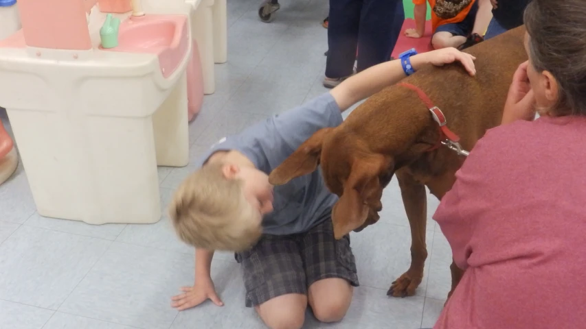 a young child is sitting on the floor with his dog