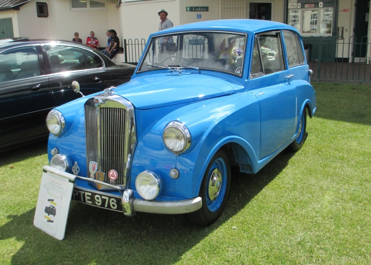 blue vintage car on display with other cars