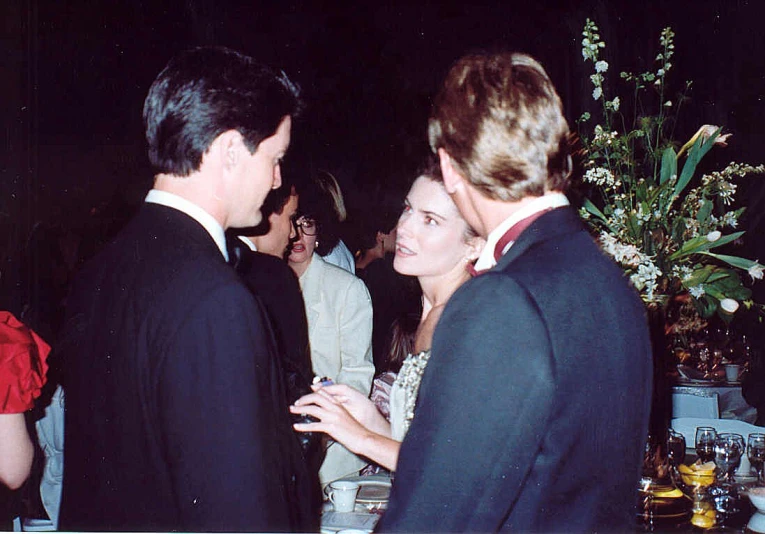 a woman standing with two men talking in a crowd