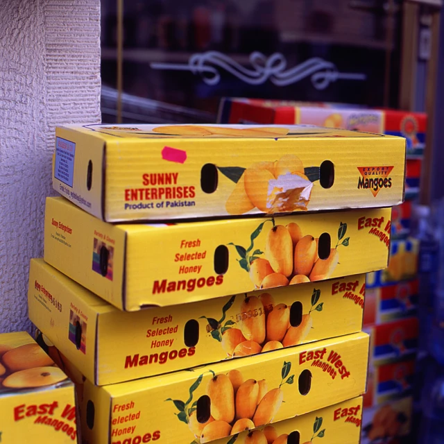 many boxes are stacked and have mangoes on them