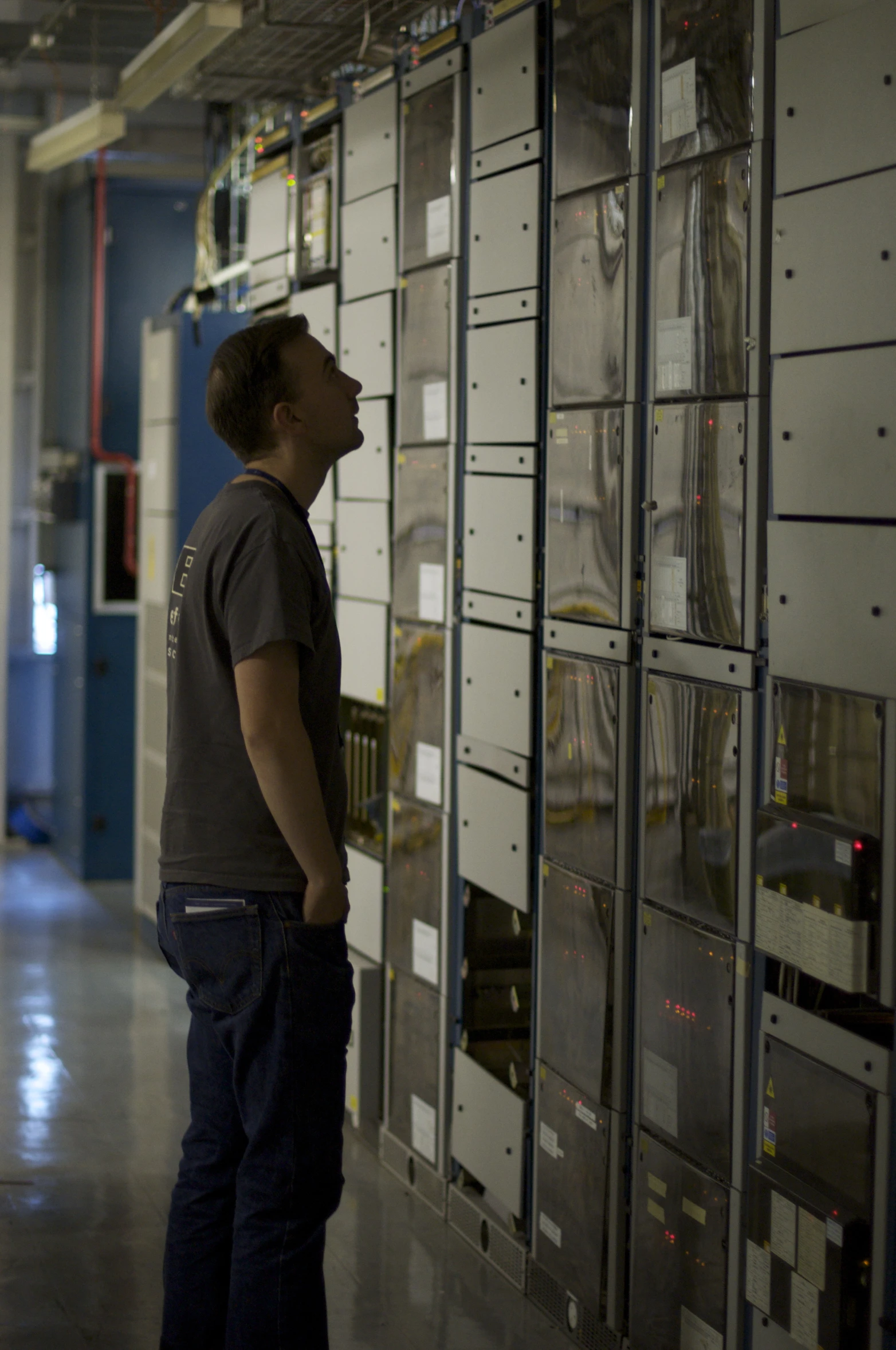 a man stands in front of a wall covered with metal boxes