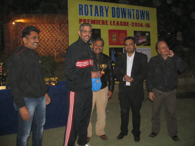 five men standing around each other by a rotary booth