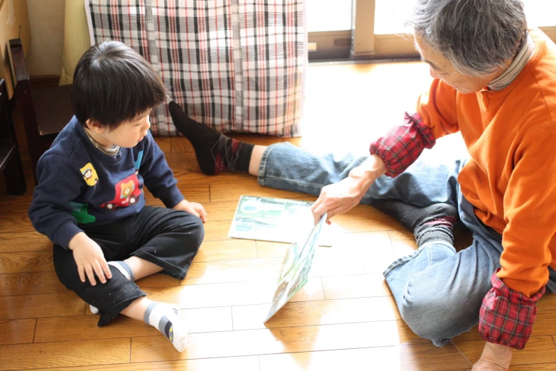 two children are sitting on the floor and they are looking at newspaper