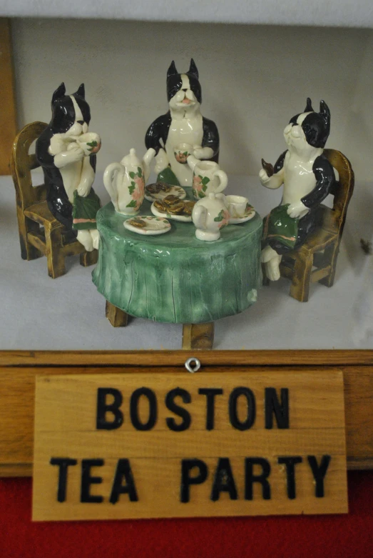 boston tea party figurines sit on display with a sign