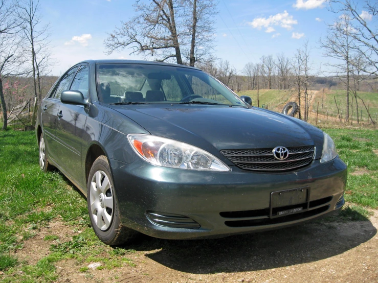 a gray car parked on the side of a dirt road