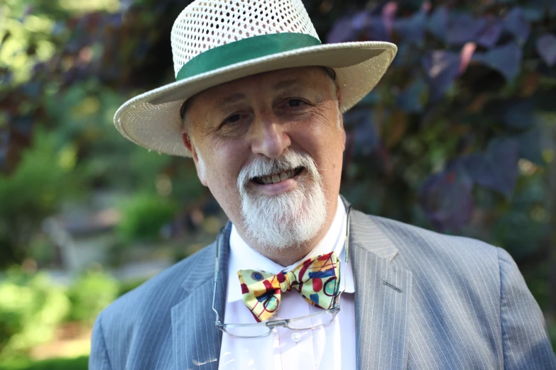 a man with a white hat and tie wearing a suit