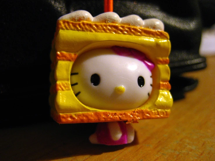 an hello kitty figurine in yellow frame sitting on a table