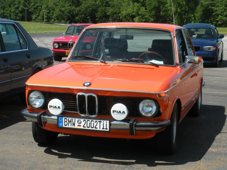 an orange car that is parked near other cars