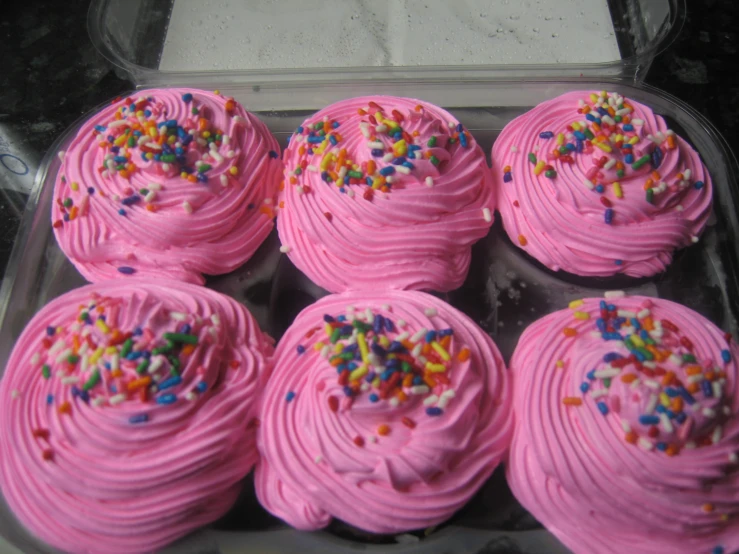 twelve decorated cupcakes in a glass container for serving