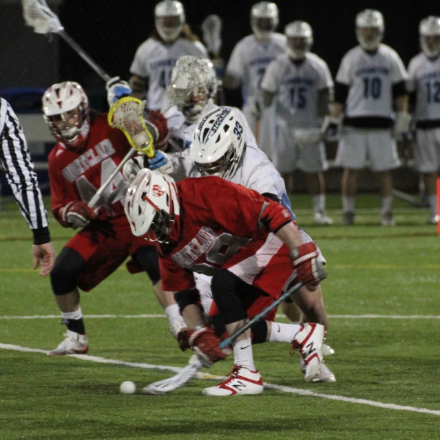 a couple of guys playing lacrosse on a field