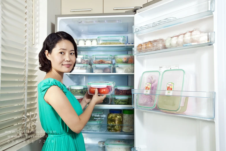 a woman is looking at the fridge with some food