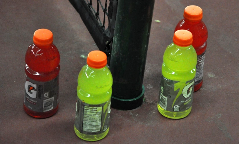 three plastic soda bottles are lined up next to a pole