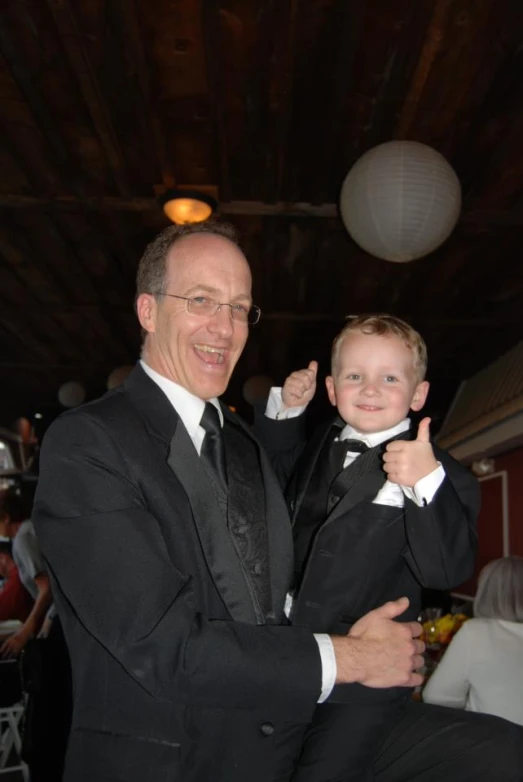 a father and son in formal wear posing for a picture