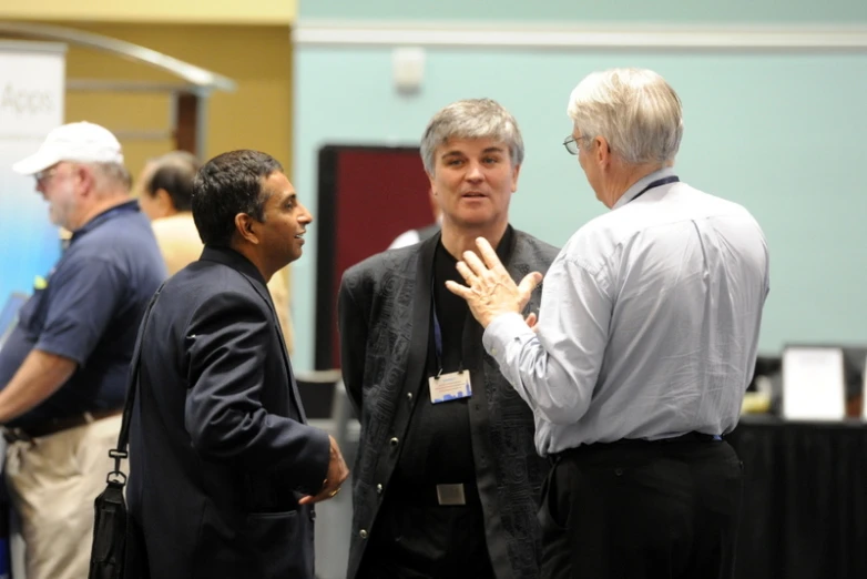 a group of men standing around talking to each other