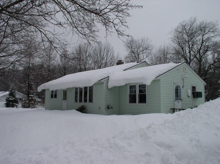 the front of a home covered in snow with some trees all around