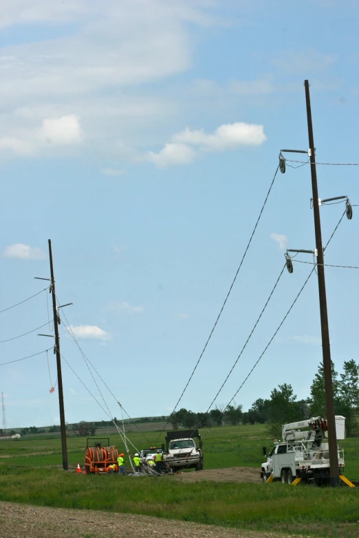 an old truck, tow trucks and a tractor is on a dirt road near the power poles