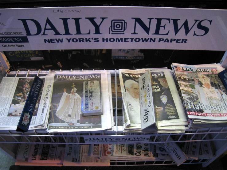 newspaper and newspapers are stacked up in a store shelf