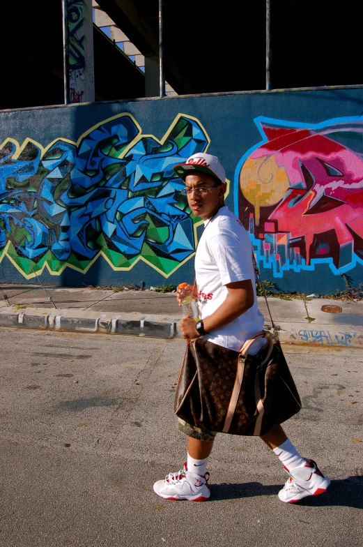 a man is walking on the sidewalk next to a wall