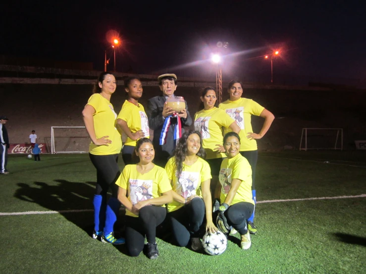 a group of people wearing yellow shirt standing on top of a soccer field