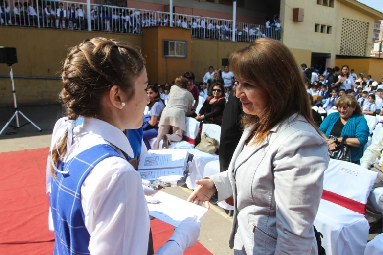 two woman having conversation outside in front of a crowd