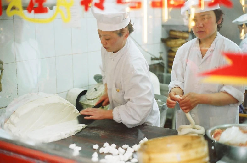 two chefs prepare food inside a kitchen in an asian restaurant