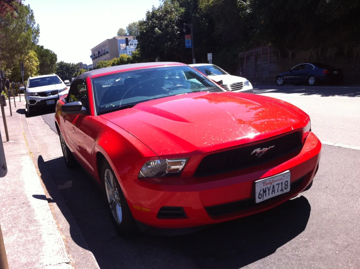 a red mustang car parked in the street