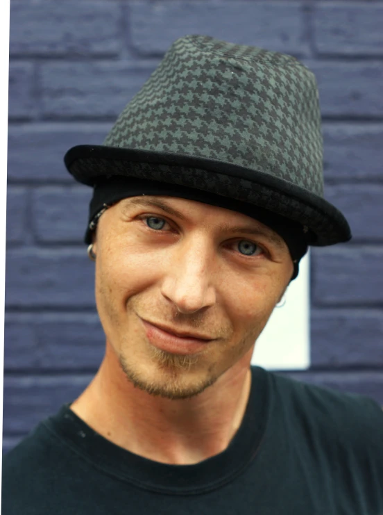 a young man wearing a hat in front of a brick wall