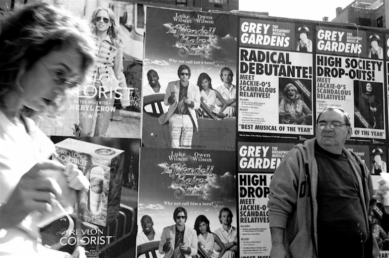 a man and woman walking in front of posters